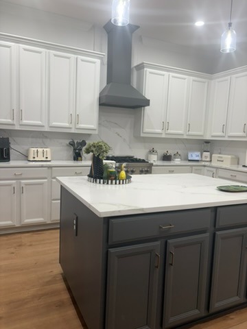 Refinished kitchen showing grey range hood and white shaker cabinets